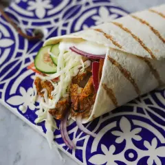 Pyszny kebab w picie z soczystym mięsem, chrupiącą surówką, pomidorem, ogórkiem i czerwoną cebulą, zawinięty w ciepły placek.
