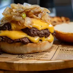 Smash burger z podwójną wołowiną, serem cheddar i karmelizowaną cebulką na bułce.