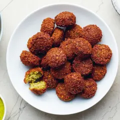 Talerz pełen chrupiących kulek falafel. Co to jest falafel? To smażone kulki z ciecierzycy, idealne do sosu tahini.