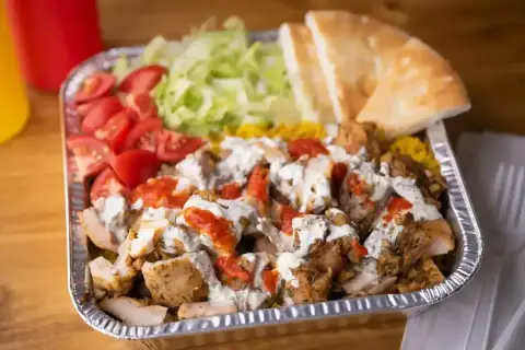 Pyszny gyros z kurczakiem, ryżem, pomidorami, sałatą i pitą, polany sosem. Idealny posiłek, by dowiedzieć się, co to jest gyros!