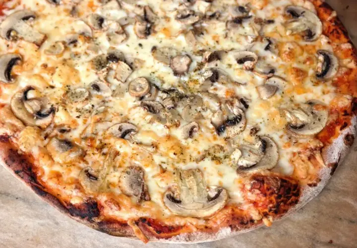 Pyszna pizza z pieczarkami, idealnie wypieczona w 180 stopniach, z ciągnącym się serem i chrupiącym ciastem.