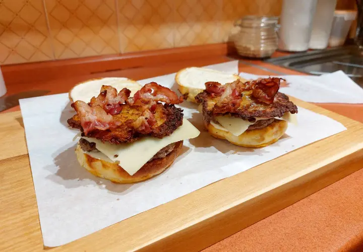 Dwa domowe burgery, przypominające kanapkę zbójnicką z McDonald's, z serem, plackiem ziemniaczanym i chrupiącym boczkiem.