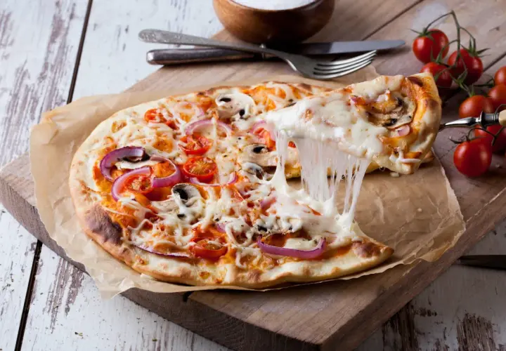Rozciągający się ser z pizzy z pomidorami, cebulą i pieczarkami na desce.