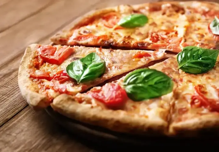 Klasyczna pizza Margherita, jak z Pizza Hut, z pomidorami i bazylią na drewnianym blacie.