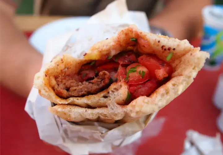 Pyszny, soczysty turecki kebab z mięsem mielonym, pomidorami i ziołami, zawinięty w chrupiące pieczywo.