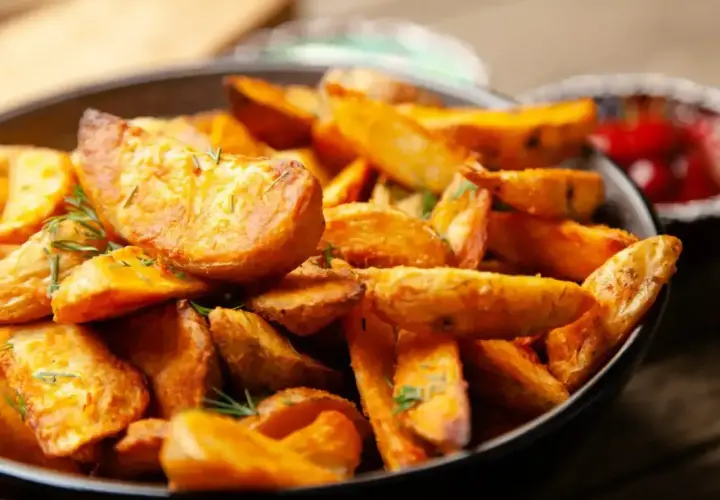 Chrupiące frytki stekowe z ziołami w misce, obok ketchup.