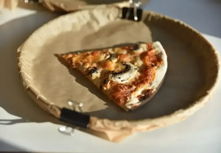 Kawałek pizzy z pieczarkami na papierowym talerzu. Duża pizza z Pizza Hut może mieć sporo kalorii, ale smakuje wybornie!
