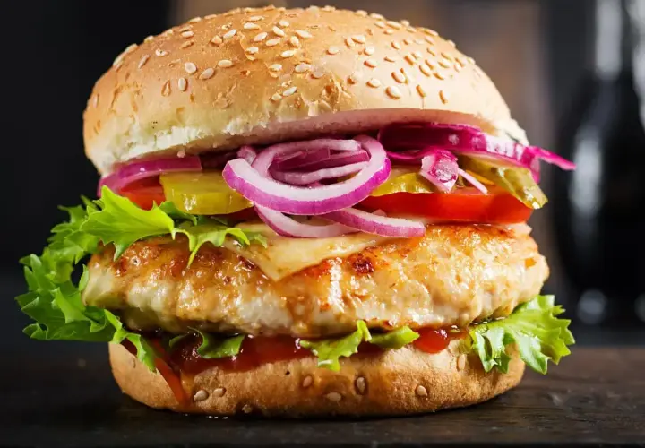 Pyszny burger z kurczakiem, sałatą, pomidorem, ogórkiem, czerwoną cebulą i roztopionym serem. Jaki ser jest w drwalu? To tajemnica, ale wygląda na pyszny!