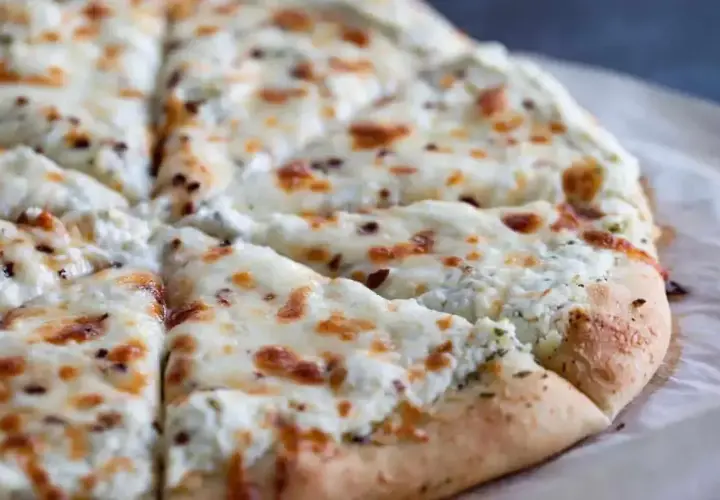 Pyszna pizza biała z serem i ziołami, pokrojona na kawałki. Idealna na szybką przekąskę.