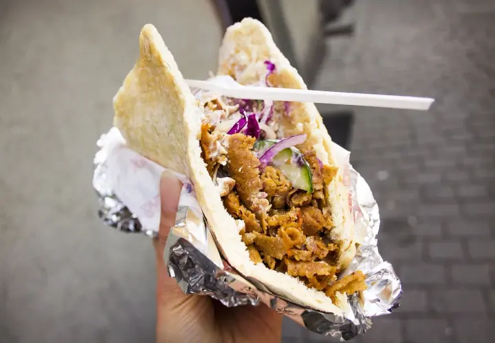 Pyszny kebab w bułce z mięsem, warzywami i sosem. To danie, które swoją popularność zawdzięcza podróżom i wymianie kulturowej, pokazując, skąd pochodzi kebab.