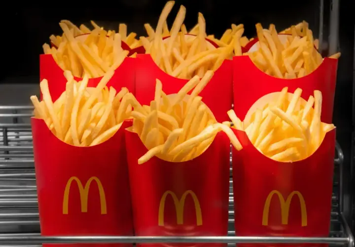 Kilka porcji świeżych, gorących, średnich frytek z McDonald's w czerwonych opakowaniach.