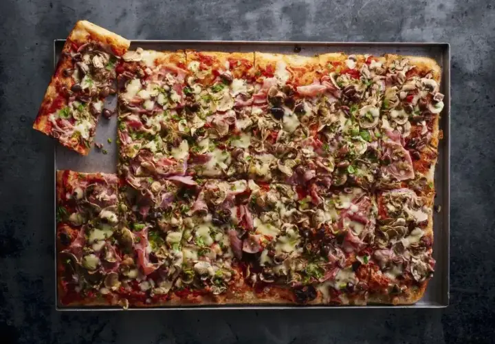 Pyszna pizza domowa przepis na blachę z szynką, pieczarkami i oliwkami. Idealna na rodzinne spotkanie.