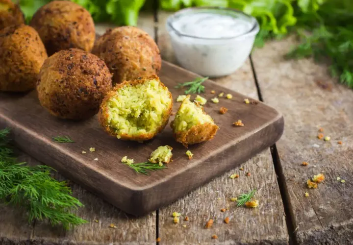 Chrupiące kulki falafel kebab na desce, obok sosu i świeżego koperku. Idealna przekąska.