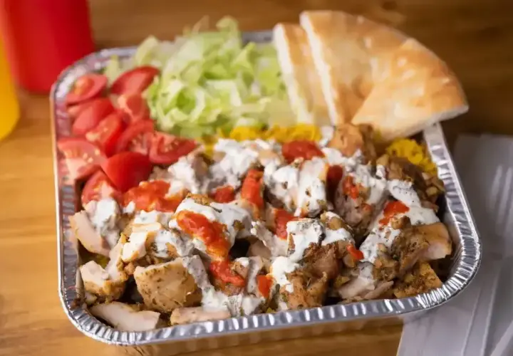 Pyszny gyros z kurczakiem, ryżem, pomidorami, sałatą i pitą, polany sosem. Idealny posiłek, by dowiedzieć się, co to jest gyros!