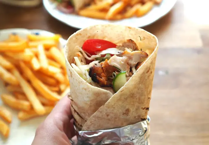 Pyszny kebab amerykański z kurczakiem, warzywami i frytkami w tle. Idealny na szybki posiłek.