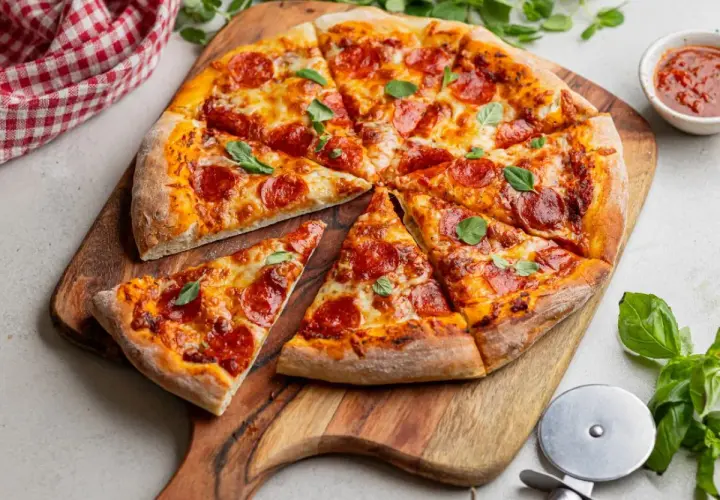 Apetyczna pizza pepperoni z ciągnącym się serem i świeżą bazylią, gotowa do podania.