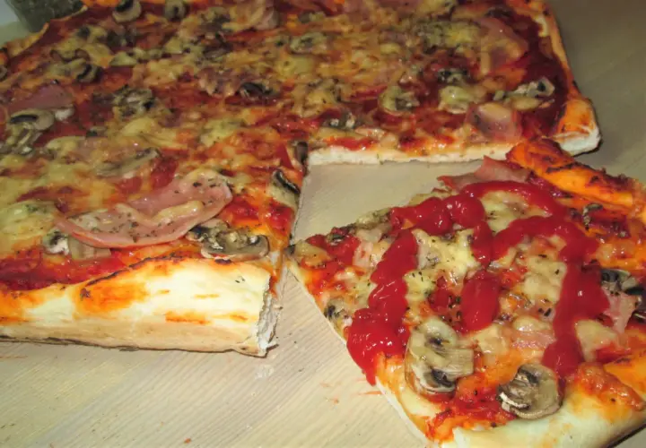 Pyszna pizza supreme z szynką i pieczarkami, polana ketchupem. Idealna na spotkanie z przyjaciółmi.