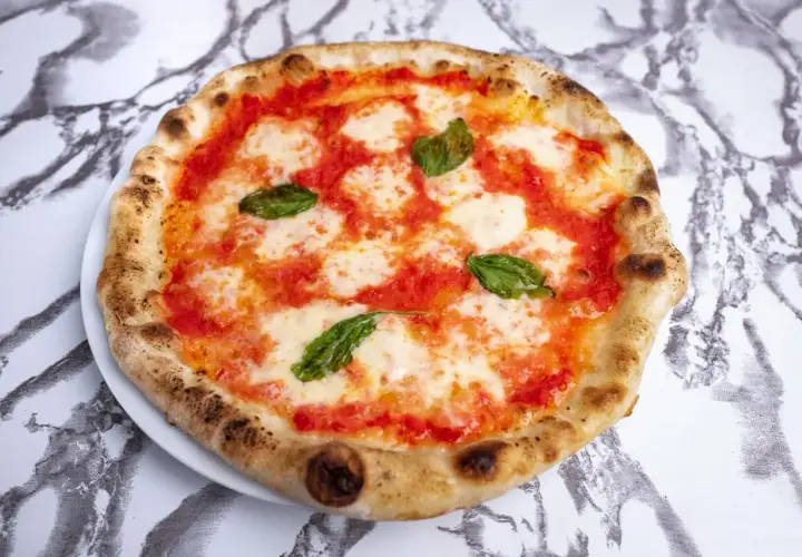 Idealne ciasto na pizzę neapolitańską, z puszystymi brzegami, sosem pomidorowym, mozzarellą i świeżą bazylią.