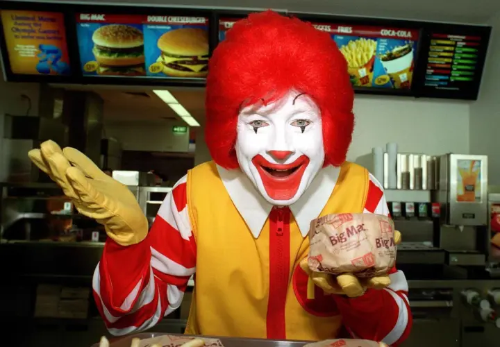 Ronald McDonald trzyma Big Maca. Zastanawiasz się, ile kosztuje red chikker? Sprawdź menu!