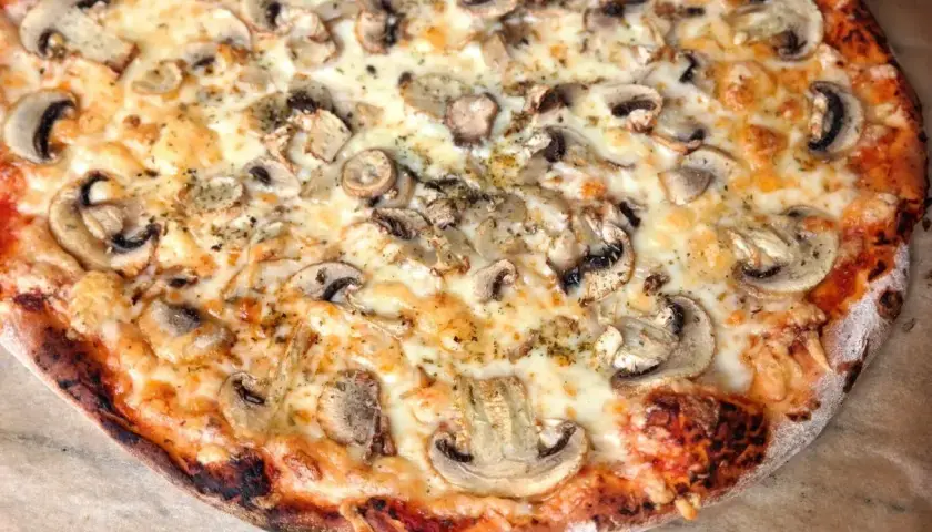 Pyszna pizza z pieczarkami, idealnie wypieczona w 180 stopniach, z ciągnącym się serem i chrupiącym ciastem.