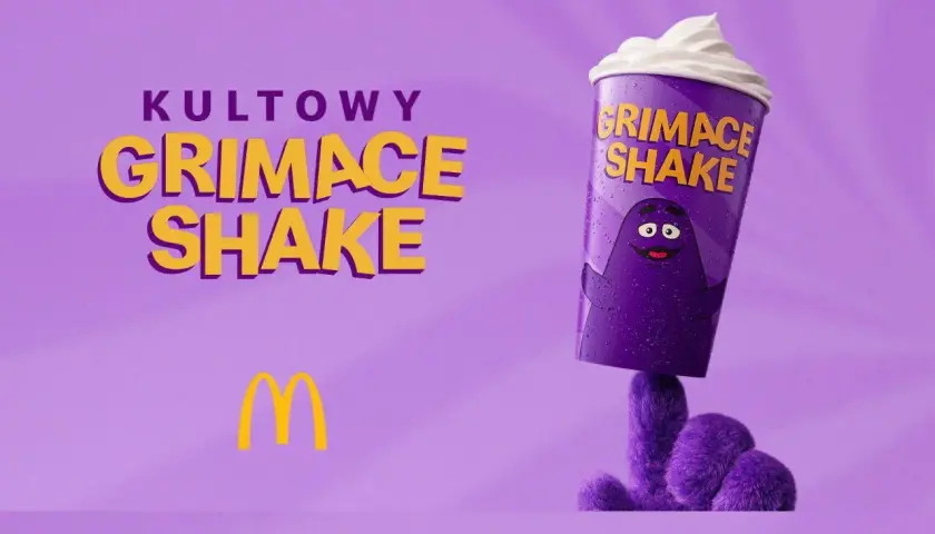 Kultowy Grimace Shake z McDonald's, ozdobiony postacią Grimace'a, na fioletowym tle.