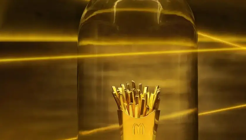 Złote frytki w pudełku McDonald's pod szklaną kopułą, jak nagroda w loterii McDonald's.