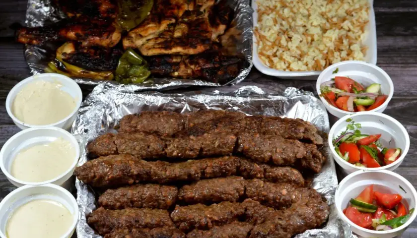 Pyszny kofta kebab z ryżem, sałatkami i sosami.