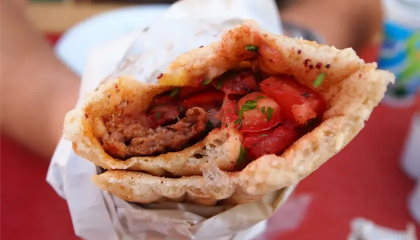 Pyszny, soczysty turecki kebab z mięsem mielonym, pomidorami i ziołami, zawinięty w chrupiące pieczywo.