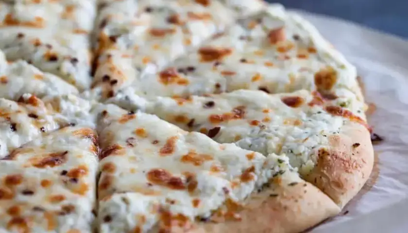 Pyszna pizza biała z serem i ziołami, pokrojona na kawałki. Idealna na szybką przekąskę.