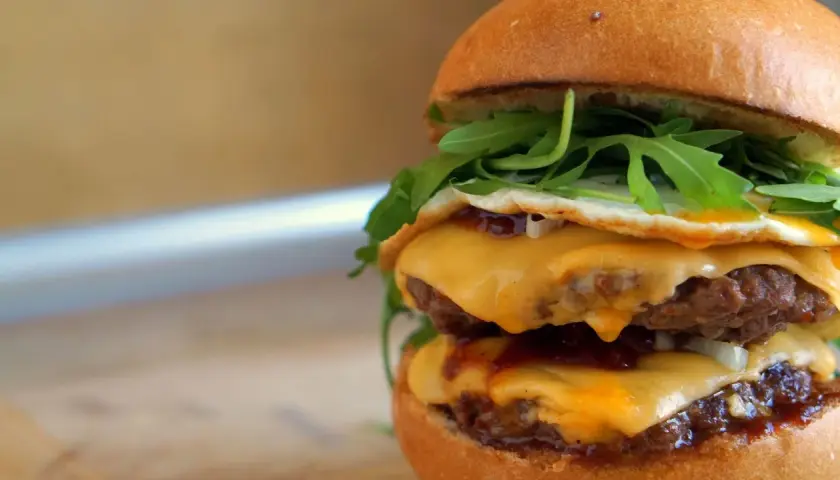 Pyszny McMuffin farmerski przepis: podwójny kotlet, ser, jajko sadzone, rukola i sos. Idealny na śniadanie!