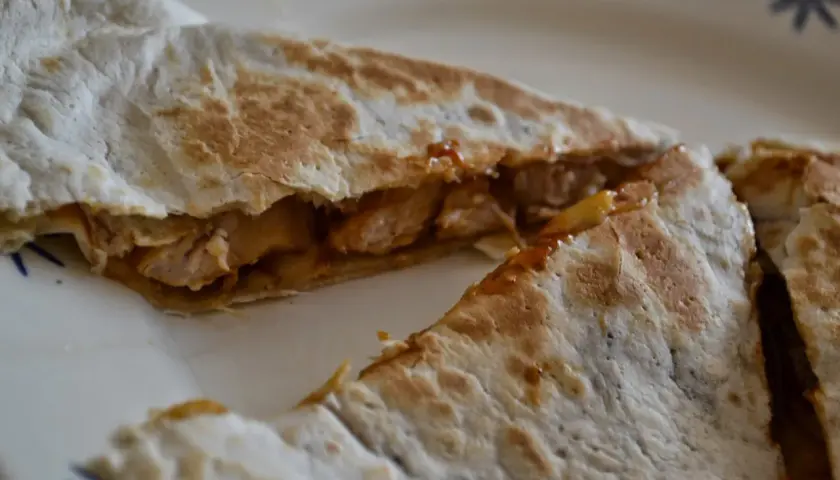 KFC Qurrito z kawałkami kurczaka i sosem, podane na talerzu.