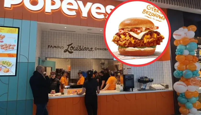 Popeyes ceny: soczysty burger z kurczakiem i bekonem, oferta sezonowa. W tle restauracja Popeyes.