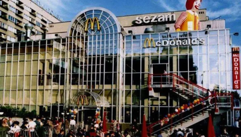 Tłum ludzi przed budynkiem z napisem "sezam" i logo McDonald's. To był pierwszy McDonald's w Polsce, otwarcie w 1992 roku.