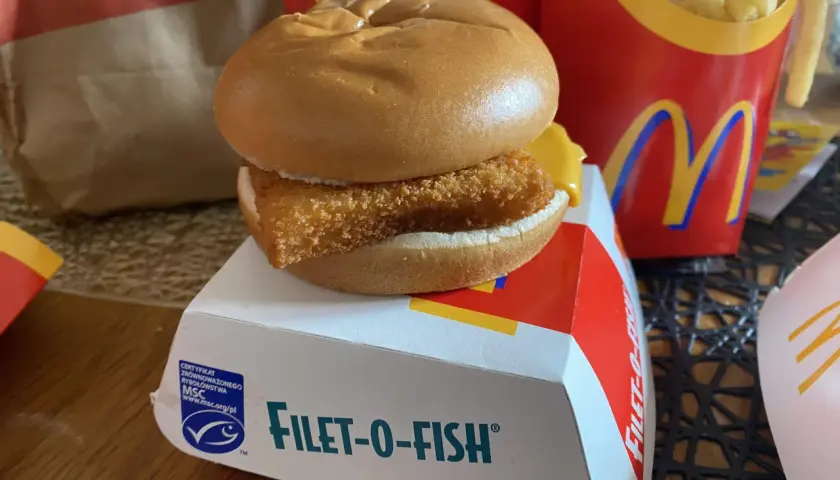 Filet-o-Fish, klasyczny fishburger z McDonald's, na białym pudełku z logo MSC. Obok frytki w czerwonym opakowaniu.