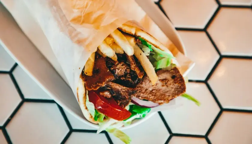 Pyszny kebab z mięsem, frytkami, warzywami i sosem. Idealny na szybki posiłek, choć warto pamiętać o jego kcal.