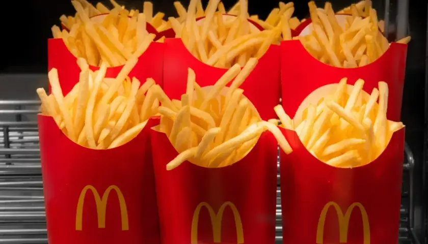 Kilka porcji świeżych, gorących, średnich frytek z McDonald's w czerwonych opakowaniach.