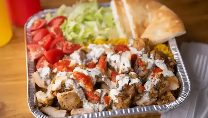 Pyszny gyros z kurczakiem, ryżem, pomidorami, sałatą i pitą, polany sosem. Idealny posiłek, by dowiedzieć się, co to jest gyros!