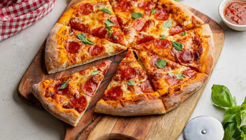 Apetyczna pizza pepperoni z ciągnącym się serem i świeżą bazylią, gotowa do podania.