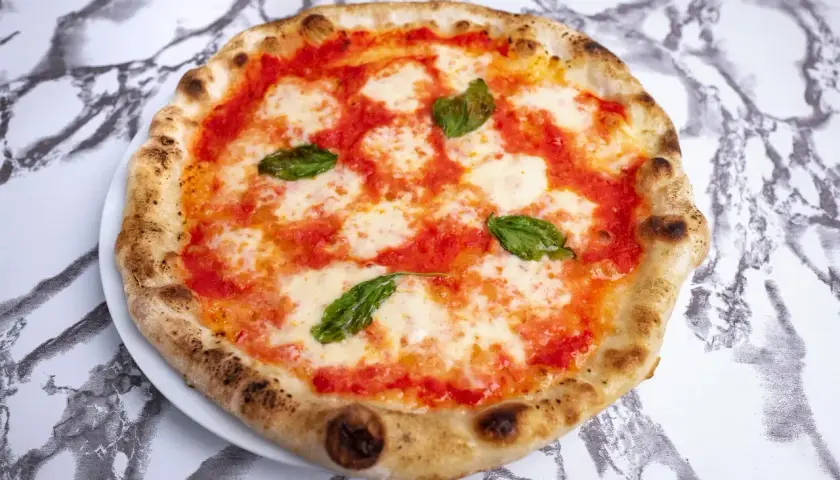 Idealne ciasto na pizzę neapolitańską, z puszystymi brzegami, sosem pomidorowym, mozzarellą i świeżą bazylią.