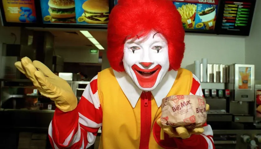 Ronald McDonald trzyma Big Maca. Zastanawiasz się, ile kosztuje red chikker? Sprawdź menu!