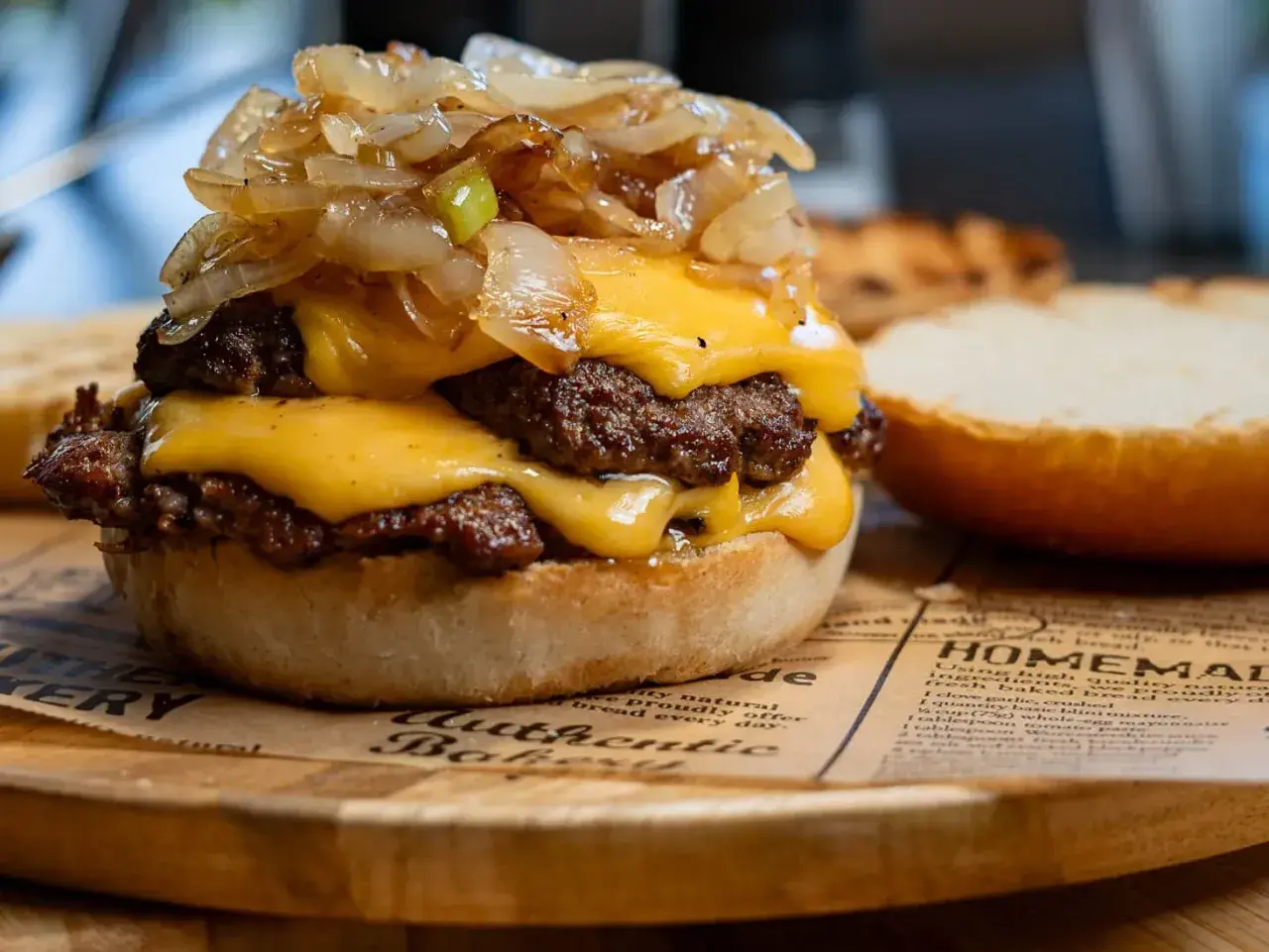 Smash burger z podwójną wołowiną, serem cheddar i karmelizowaną cebulką na bułce.