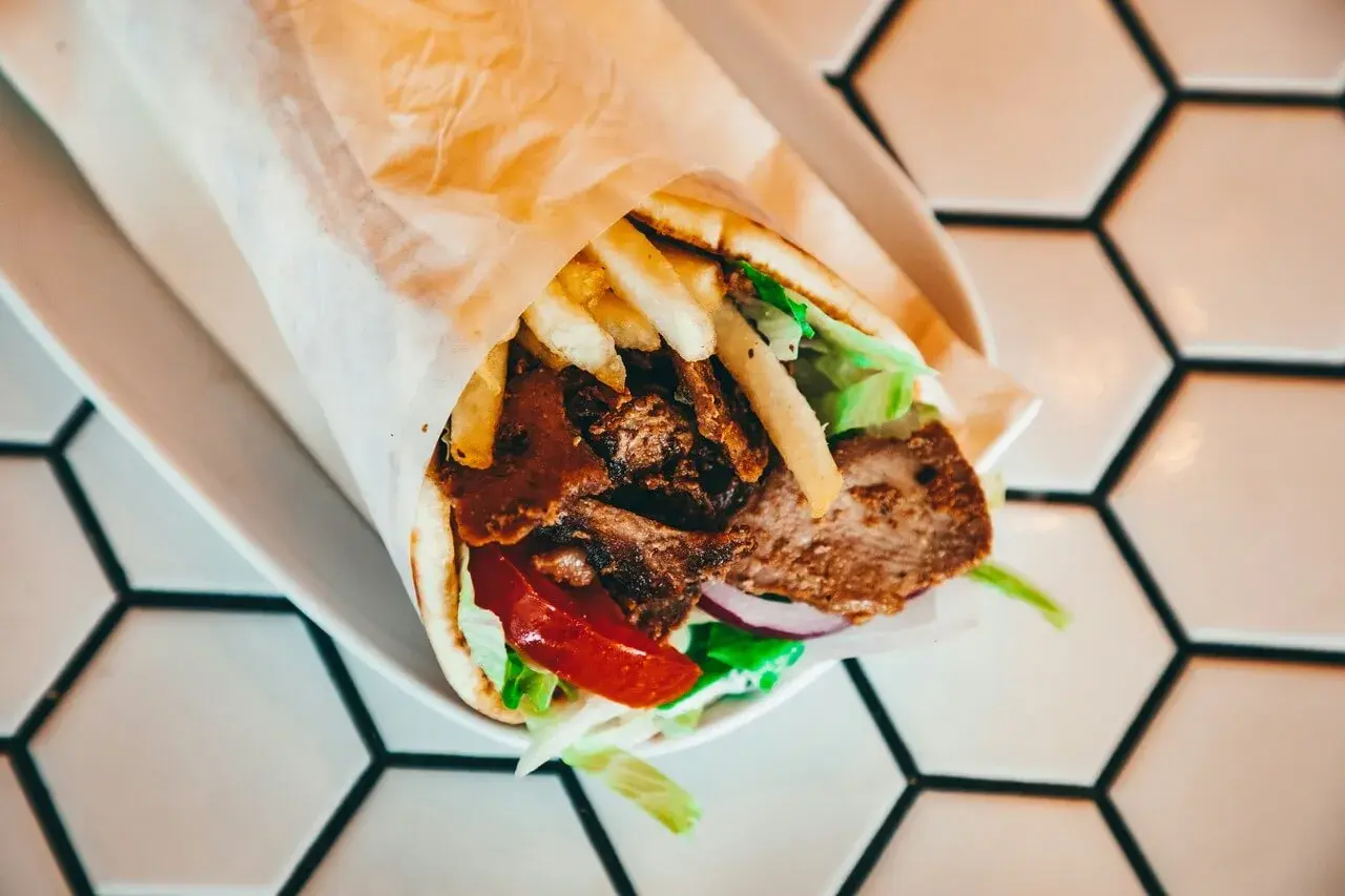 Pyszny kebab z mięsem, frytkami, warzywami i sosem. Idealny na szybki posiłek, choć warto pamiętać o jego kcal.