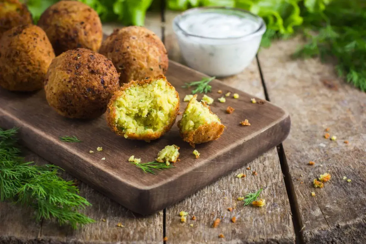 Chrupiące kulki falafel kebab na desce, obok sosu i świeżego koperku. Idealna przekąska.