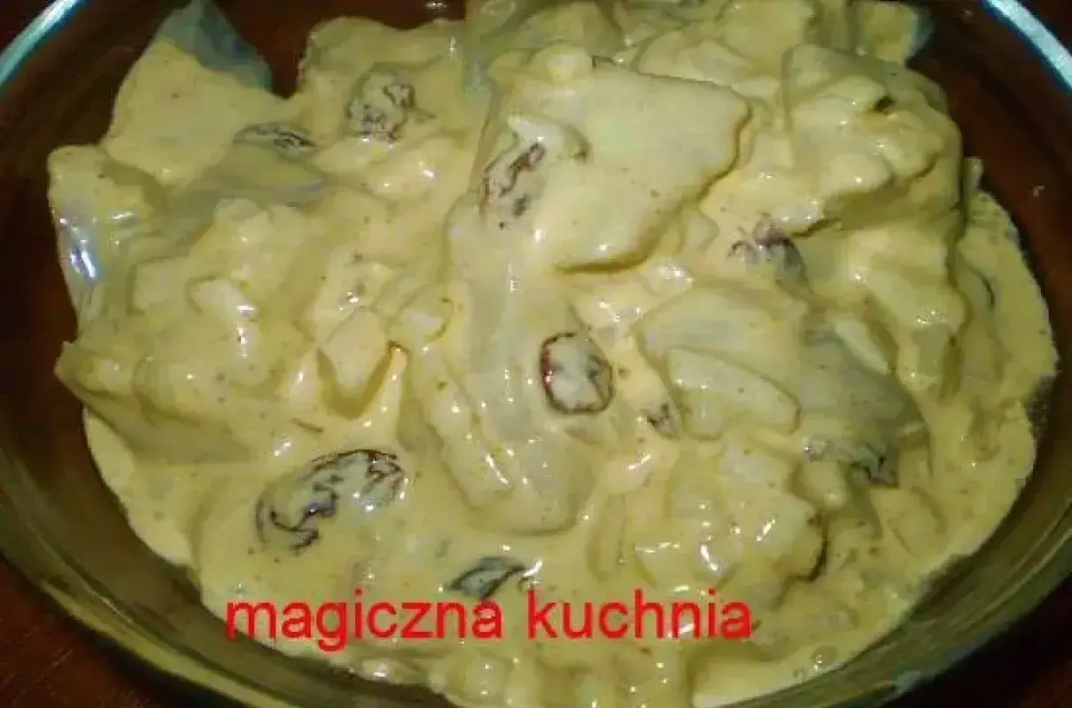 Kremowy sos golden mayo z kawałkami kurczaka i rodzynkami, serwowany w szklanej misce.
