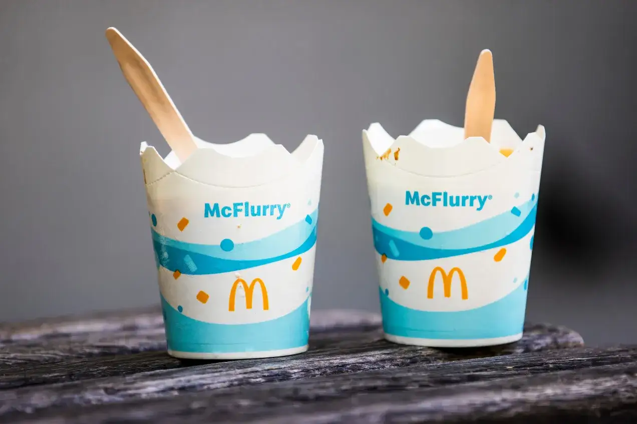 Dwa kubeczki McFlurry zimowe z drewnianymi łyżeczkami, gotowe do rozkoszowania się lodami.