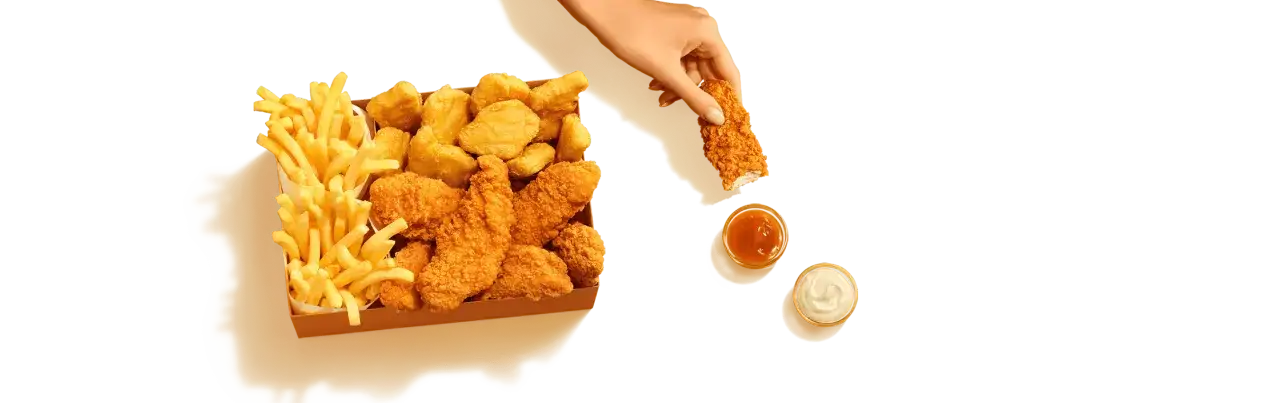 Pudełko z kurczakiem McDonald's: chrupiące kawałki kurczaka, nuggetsy i frytki, gotowe do zanurzenia w sosie.