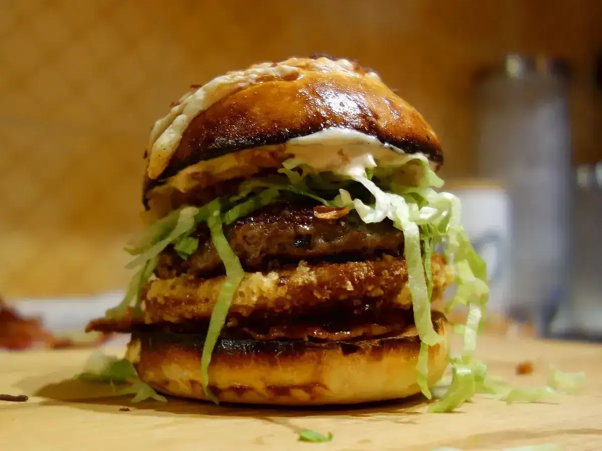 Apetyczny burger z dwoma kotletami, chrupiącą panierką, sałatą i sosem. Idealne big mac składniki.