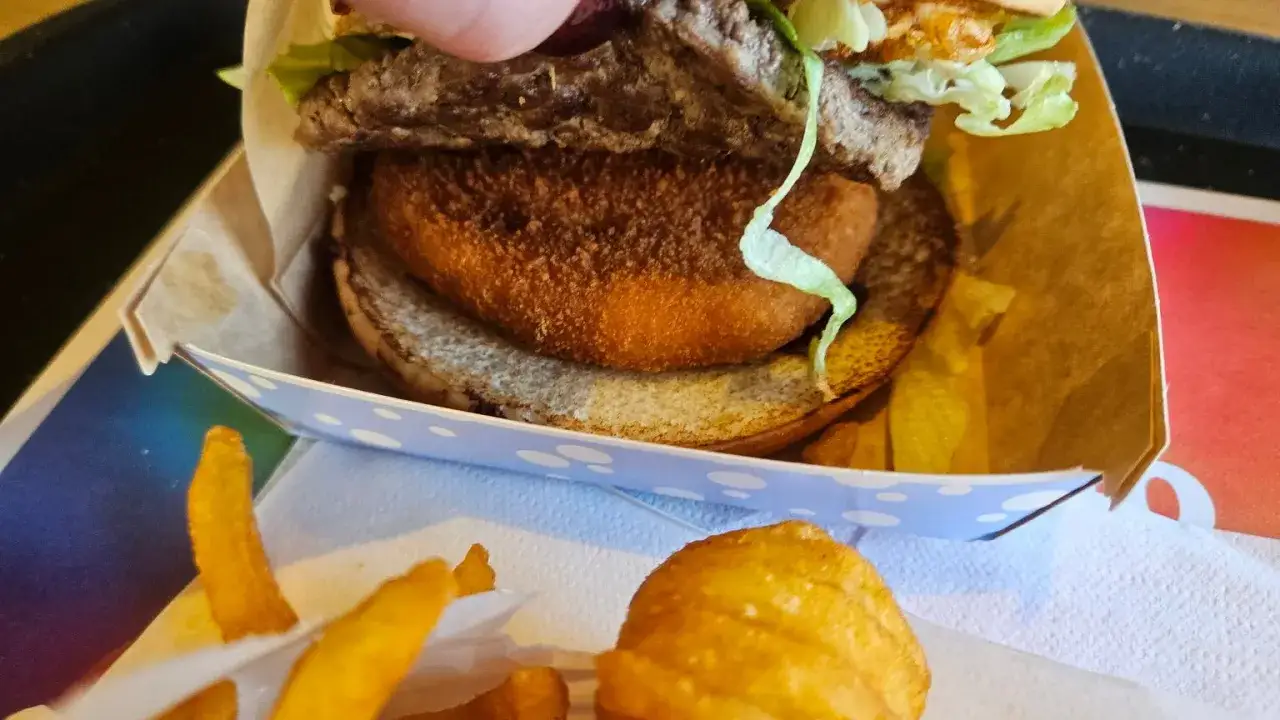 Drwal z kurczakiem w burgerze, otoczony frytkami.