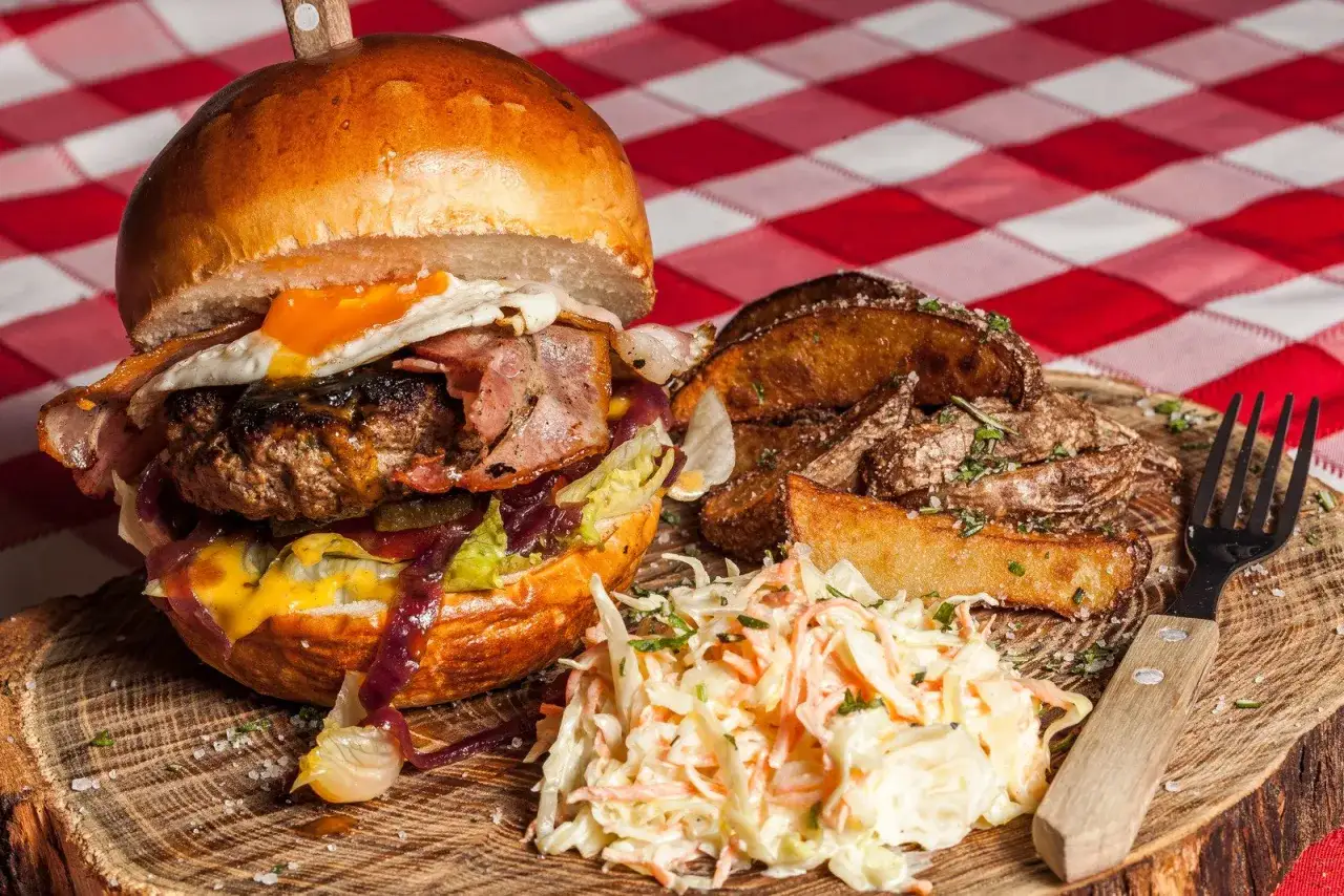 Pyszny burger z jajkiem sadzonym i bekonem, ziemniaki i surówka. Pytanie, skąd pochodzą hamburgery, jest równie intrygujące, co ten posiłek.