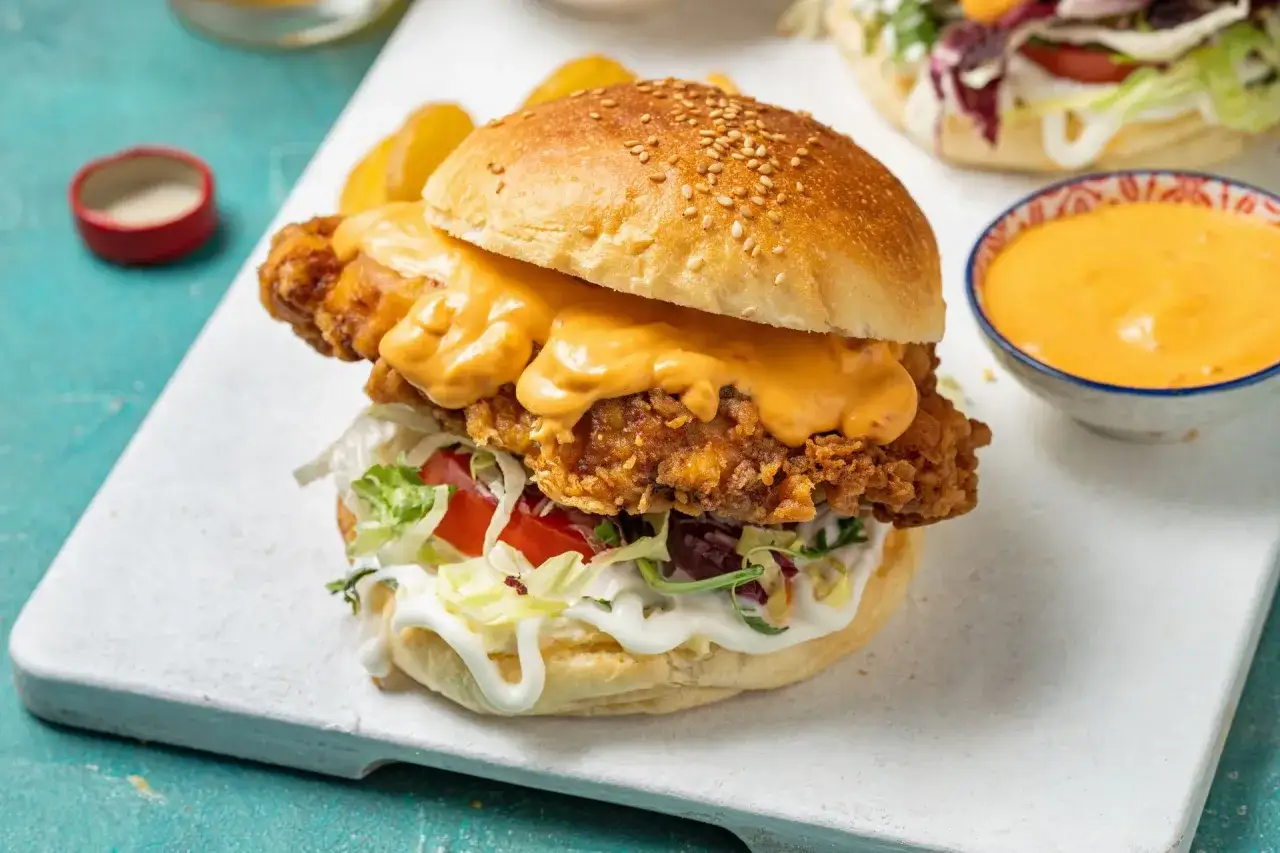 Soczysty burger z chrupiącym kurczakiem, polany sosem serowym. Wygląda grander niż kiedykolwiek!